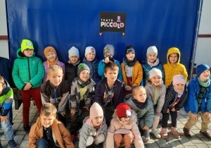 Grupa dzieci pozujących do zdjęcia przy plandece z napisem teatr Piccolo