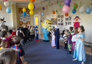 Przedszkolaki tańczą w kole z maskotką minionka