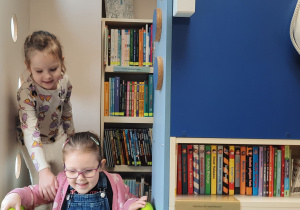 Dzieci bawią się na zjeżdżalni w bibliotecznym kąciku.