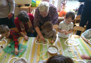 Dzieci wspólnie z dziadkami wykonują pracę plastyczną.