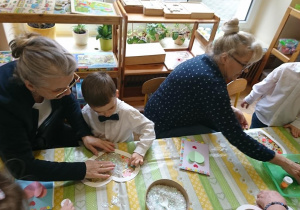 Dzieci wspólnie z dziadkami wykonują pracę plastyczną.