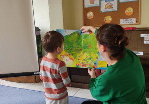Nauczycielka pokzauje dziecku miasto Łódź na mapie Polski