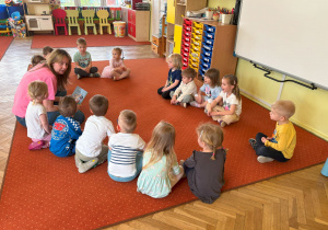 dzieci siedzą w kole i słuchają bajki