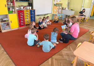 dzieci siedzą w kole i słuchają bajki