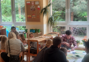 Rodzice wspólnie z dziećmi wykonują pracę plastyczną.