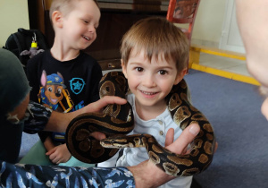 Chłopiec trzyma na szyi węża
