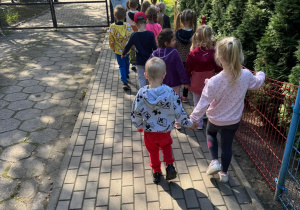 Dzieci z nauczycielem poruszają się po chodniku