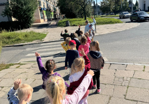Dzieci pod opieką nauczyciela przechodza bezpiecznie przez jezdnię