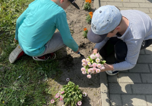 dzieci sadzą kwiatki wzdłuż krawężnika