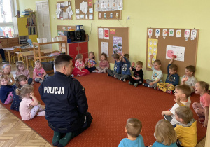 Dzieci siedzą na dywanie z Policjantem