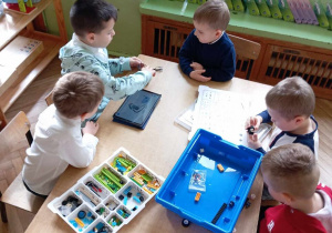 Dzieci układają klocki lego według instrukcji.