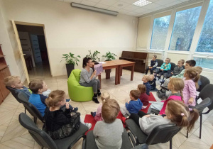 Dzieci słuchają książki czytanej przez bibliotekarkę