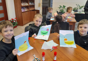 Dzieci pokazują swoje prace plastyczne.