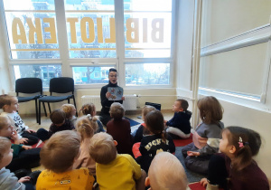Dzieci słuchają książki czytanej przez Panią bibliotekarkę.