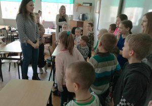 Dzieci w sali lekcyjnej słuchają nauczycielki