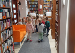 Dzieci szukają pisanek ukrytych między bibliotecznymi regałami.