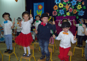 Dzieci tańczące z pałeczkami na krzesełkach